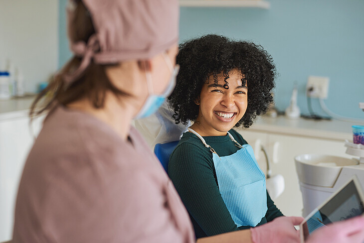 Shot of a young dentist using a tablet during a consultation with her patient