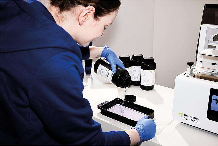 Dental technician filling liquid LuxaPrint material into the 3D printer